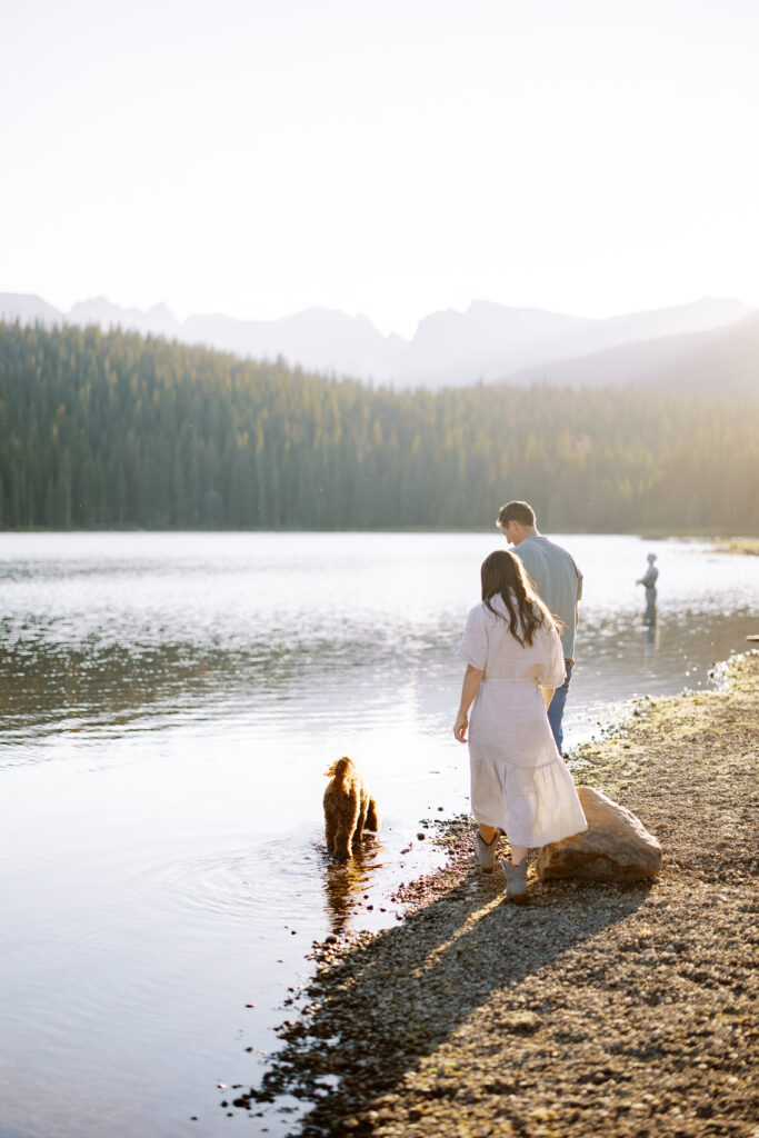 Romantic couple walking along the lake shore with mountain views behind them