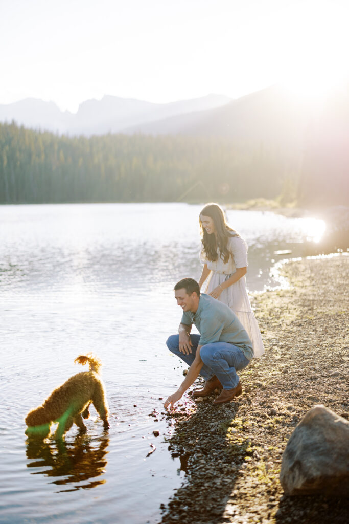 Adventure couple standing on lakeshore with their pup